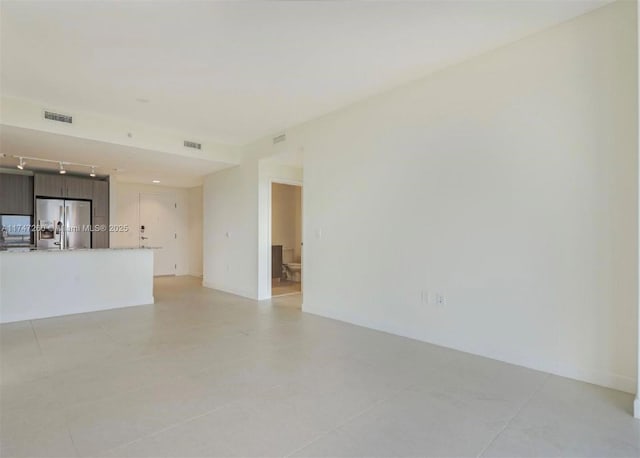 unfurnished living room featuring track lighting