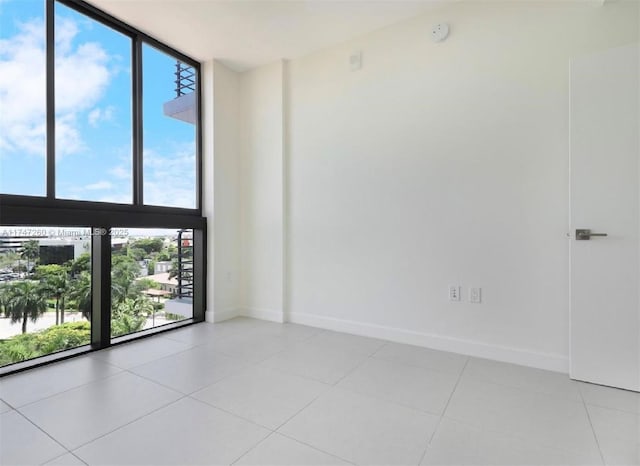 unfurnished room with light tile patterned flooring and a wall of windows