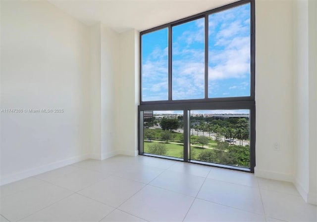 unfurnished room with light tile patterned floors and a wall of windows