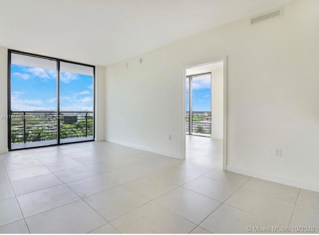 empty room with expansive windows, baseboards, and light tile patterned floors