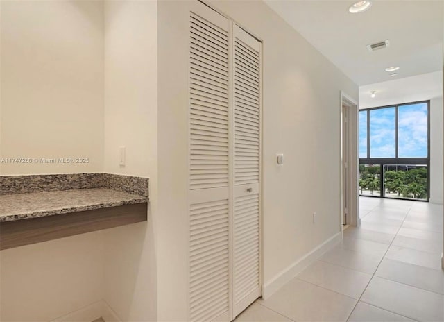 corridor with baseboards, light tile patterned flooring, and recessed lighting