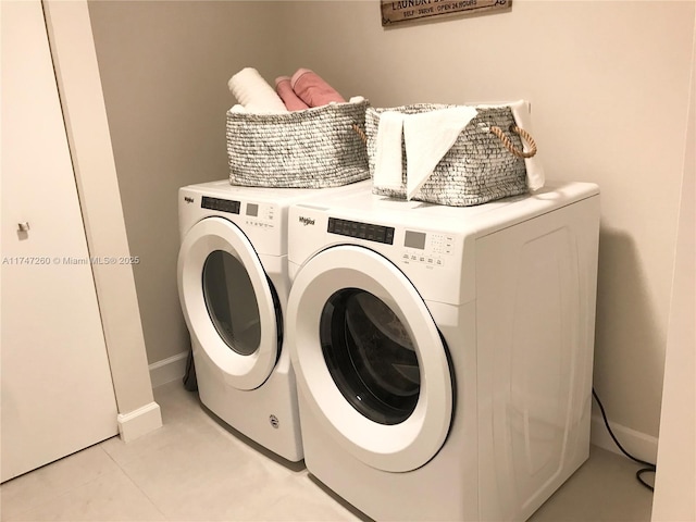 clothes washing area featuring washing machine and clothes dryer, baseboards, and light tile patterned flooring