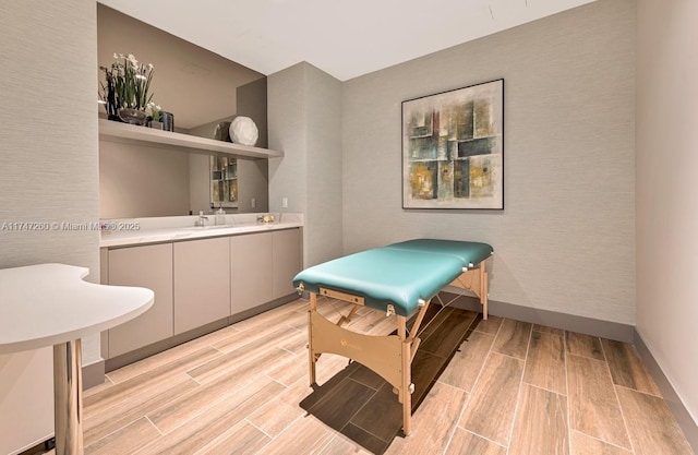 rec room featuring wood tiled floors, wet bar, and baseboards