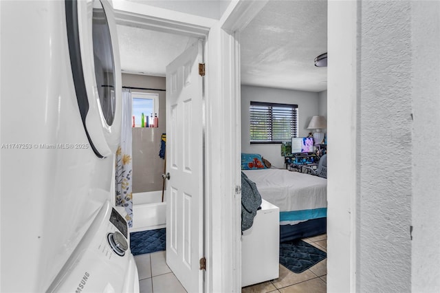 interior space featuring light tile patterned floors, laundry area, a textured ceiling, and a textured wall