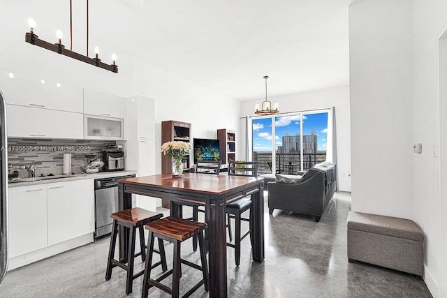 kitchen with stainless steel dishwasher, white cabinets, an inviting chandelier, and hanging light fixtures