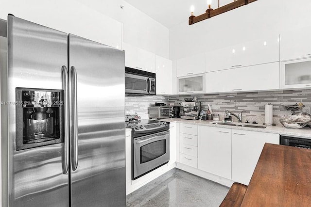 kitchen with white cabinets, appliances with stainless steel finishes, sink, and tasteful backsplash