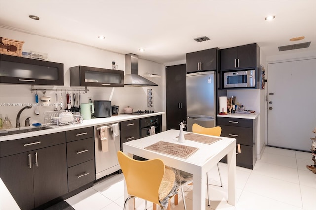 kitchen featuring visible vents, wall chimney exhaust hood, appliances with stainless steel finishes, light countertops, and a sink