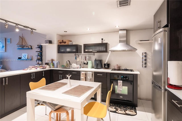 kitchen with a sink, visible vents, light countertops, black appliances, and wall chimney exhaust hood