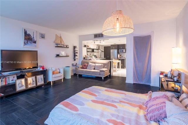 bedroom with freestanding refrigerator, wood finished floors, and visible vents