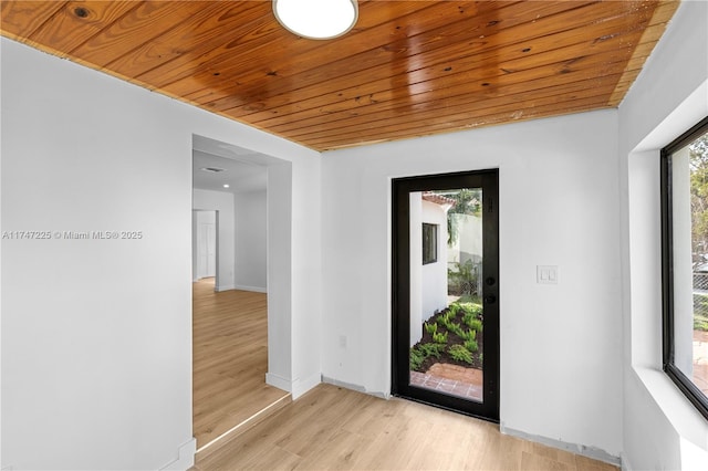 spare room featuring baseboards, wood ceiling, and light wood-style floors