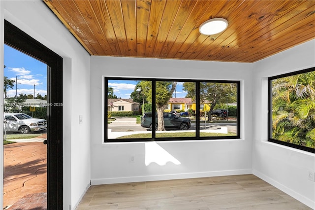 unfurnished room with a residential view, wood ceiling, light wood-style flooring, and baseboards