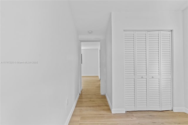 hallway with light wood-type flooring and baseboards