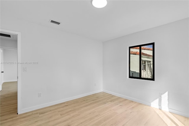 unfurnished room with light wood finished floors, visible vents, and baseboards