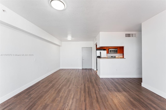 unfurnished living room featuring dark wood-type flooring and a textured ceiling