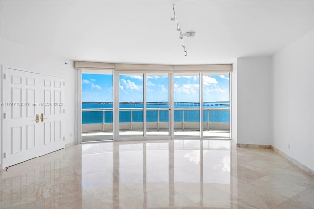 unfurnished room featuring expansive windows and a water view