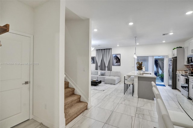 kitchen featuring visible vents, a breakfast bar, stainless steel appliances, light countertops, and recessed lighting