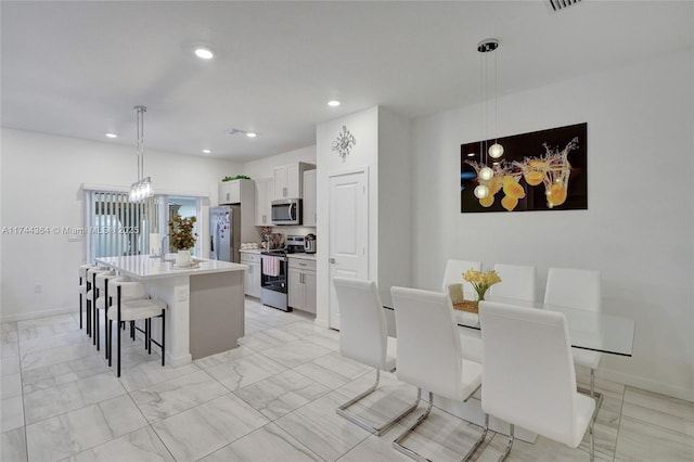 kitchen with a center island, stainless steel appliances, light countertops, white cabinets, and a kitchen bar