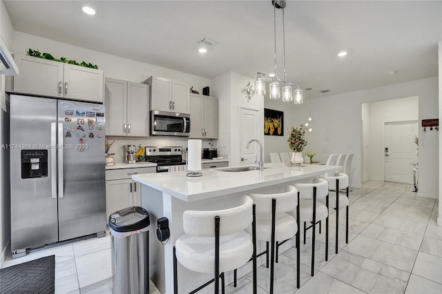 kitchen with marble finish floor, stainless steel appliances, a sink, and light countertops