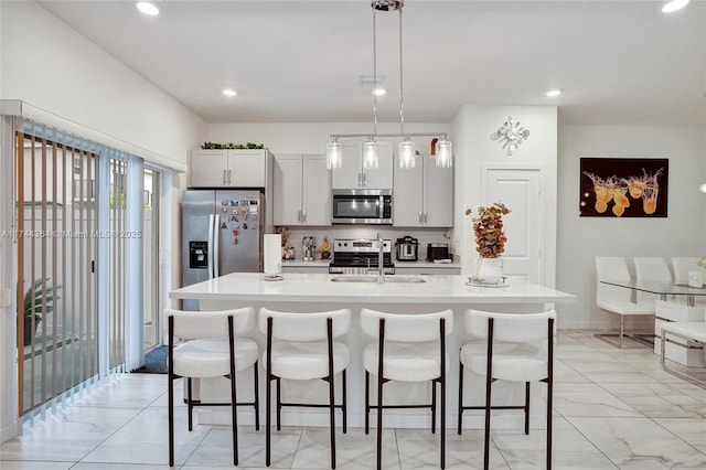 kitchen featuring appliances with stainless steel finishes, light countertops, a sink, and a kitchen bar