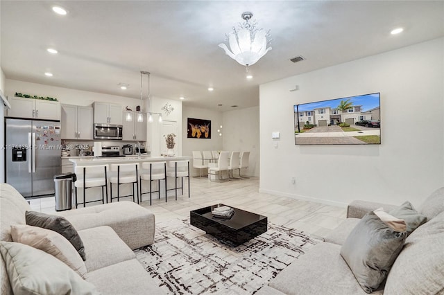 living room with baseboards, visible vents, and recessed lighting