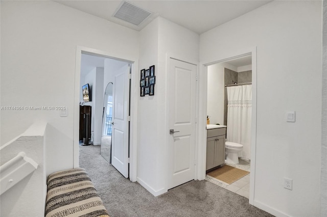 corridor featuring baseboards, visible vents, and carpet flooring