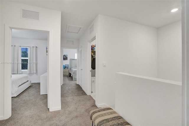 hall featuring attic access, visible vents, and carpet flooring