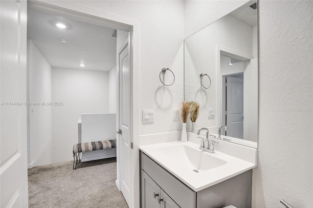 bathroom featuring a textured wall, visible vents, and vanity