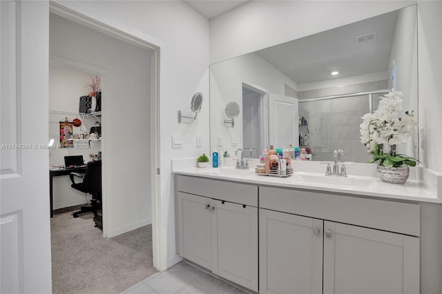 bathroom featuring double vanity, a shower stall, a spacious closet, and a sink