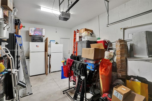 garage featuring concrete block wall, freestanding refrigerator, and a garage door opener