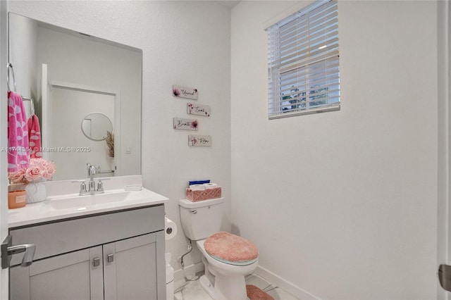 bathroom featuring toilet, baseboards, and vanity