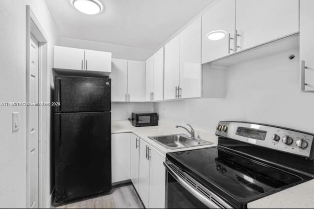 kitchen with light hardwood / wood-style floors, white cabinetry, sink, and black appliances