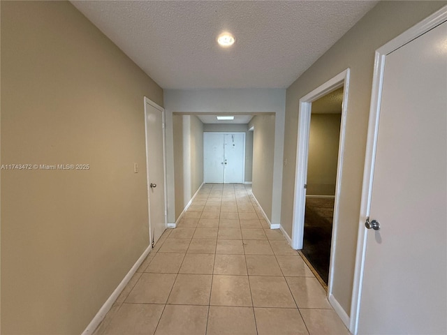 corridor with light tile patterned floors and a textured ceiling