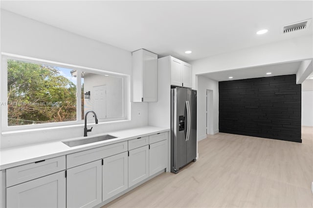 kitchen with white cabinets, light hardwood / wood-style flooring, sink, and stainless steel refrigerator with ice dispenser