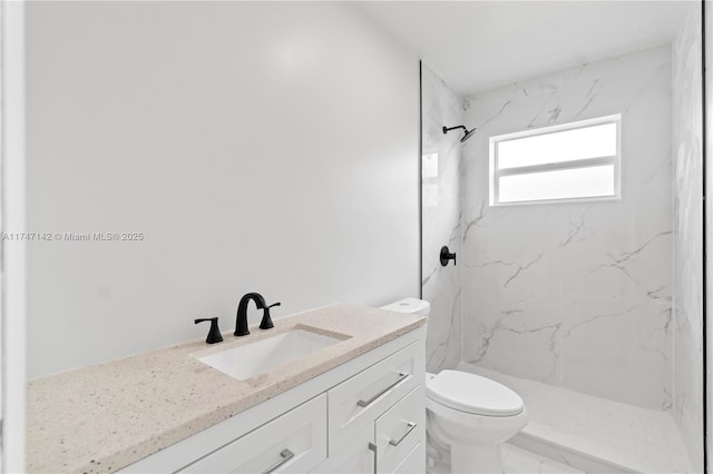 bathroom with vanity, tiled shower, and toilet