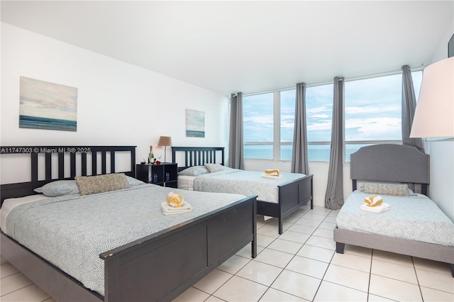 bedroom featuring a water view and light tile patterned floors