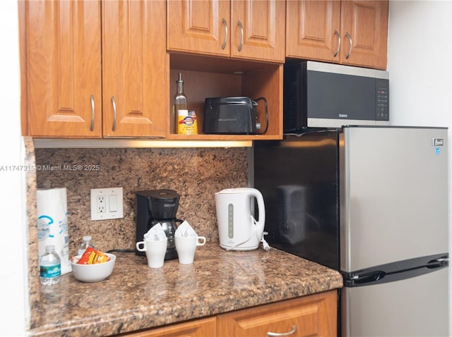 kitchen with appliances with stainless steel finishes, decorative backsplash, and dark stone counters