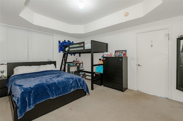 carpeted bedroom featuring a tray ceiling and a textured ceiling