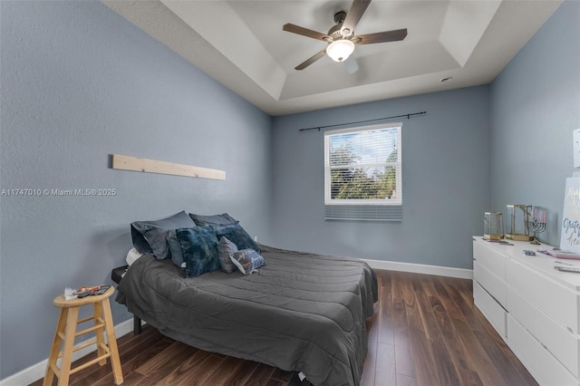 bedroom featuring dark wood-type flooring, ceiling fan, and a raised ceiling