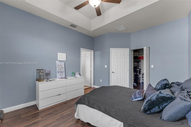 bedroom featuring dark hardwood / wood-style flooring, ceiling fan, and a raised ceiling