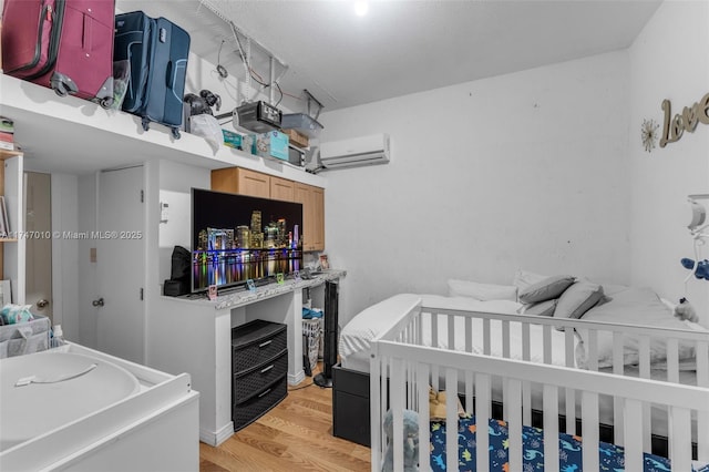 bedroom featuring an AC wall unit and light hardwood / wood-style flooring