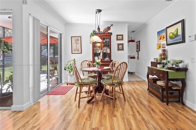 dining area featuring baseboards, light wood-style flooring, and crown molding