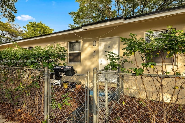 doorway to property featuring a gate, fence, and stucco siding