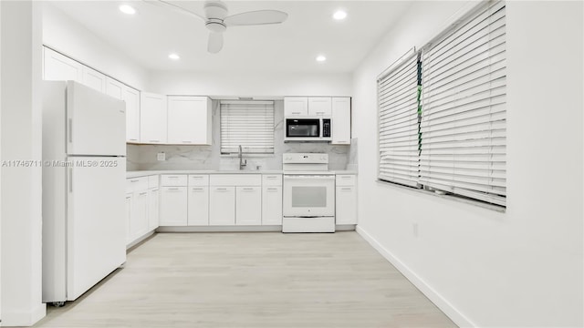 kitchen with tasteful backsplash, light countertops, white cabinets, a sink, and white appliances