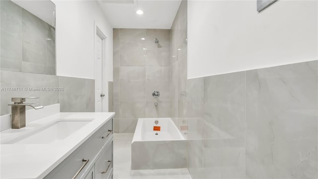 bathroom with a tub, walk in shower, tile walls, and vanity