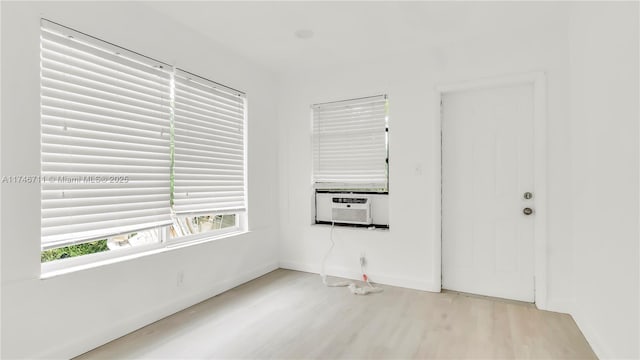 unfurnished room featuring cooling unit and light wood-style flooring