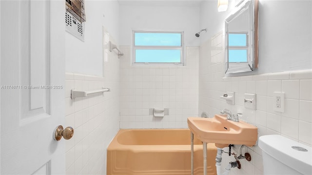 full bath featuring toilet, washtub / shower combination, a sink, and tile walls