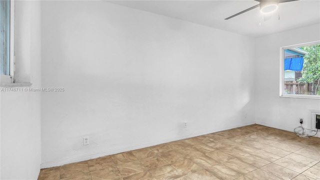 empty room with ceiling fan and baseboards