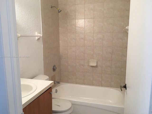 full bathroom featuring vanity, tiled shower / bath, and toilet