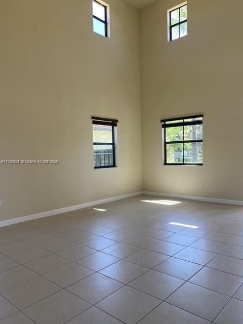 tiled spare room with a high ceiling and a healthy amount of sunlight