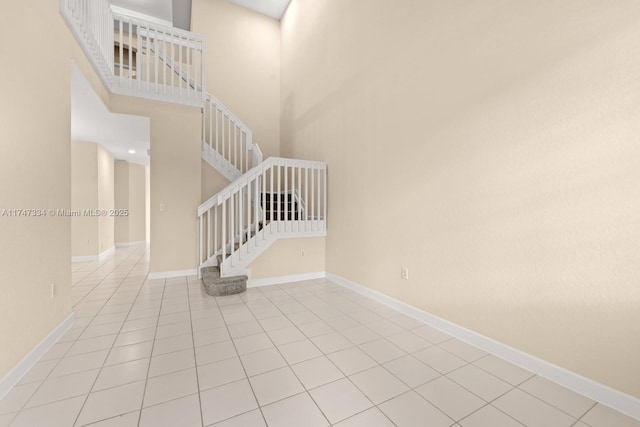 stairway with tile patterned flooring and a high ceiling